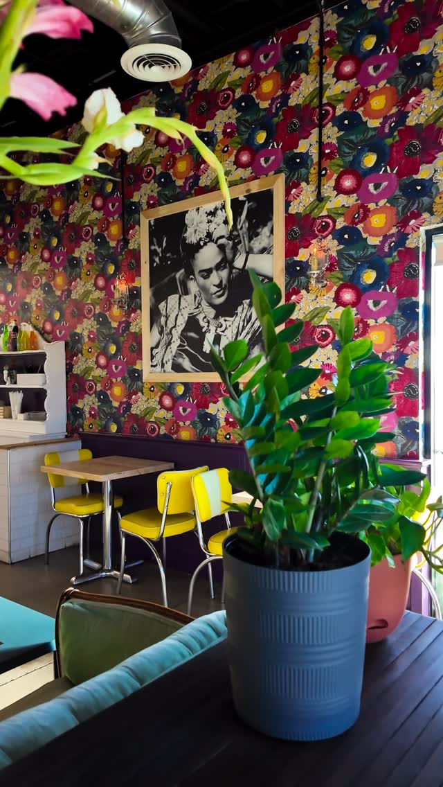 Colorful floral mural and Frida Kahlo print inside Desayuno Cafe's dining room