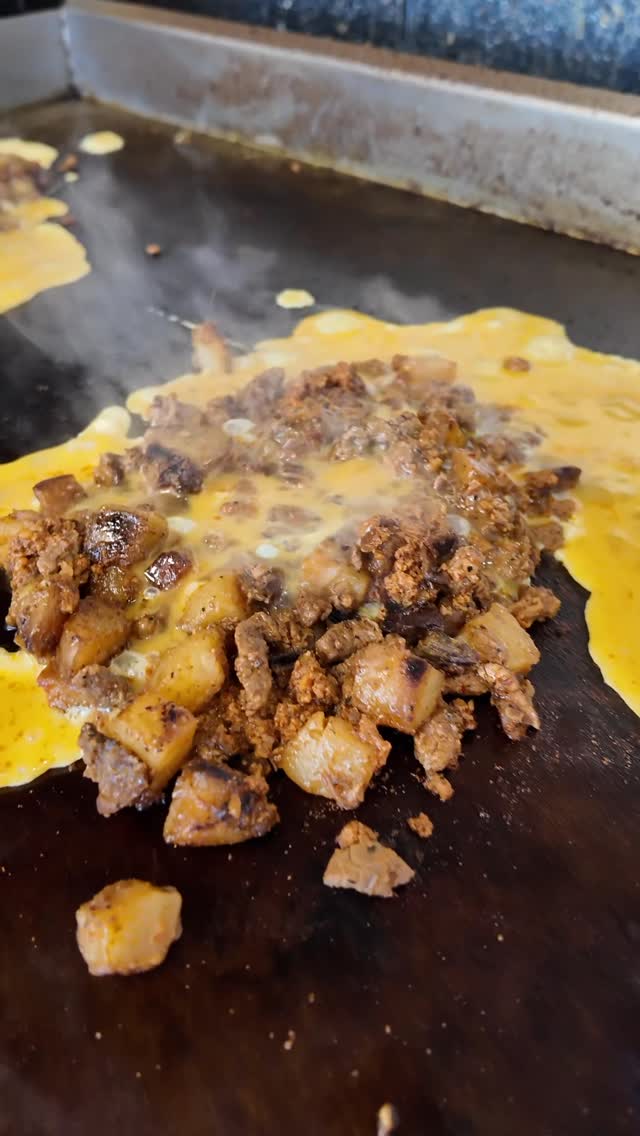 Carne asada, potatoes and egg cooking on the flat-top griddle for a Desayuno burrito