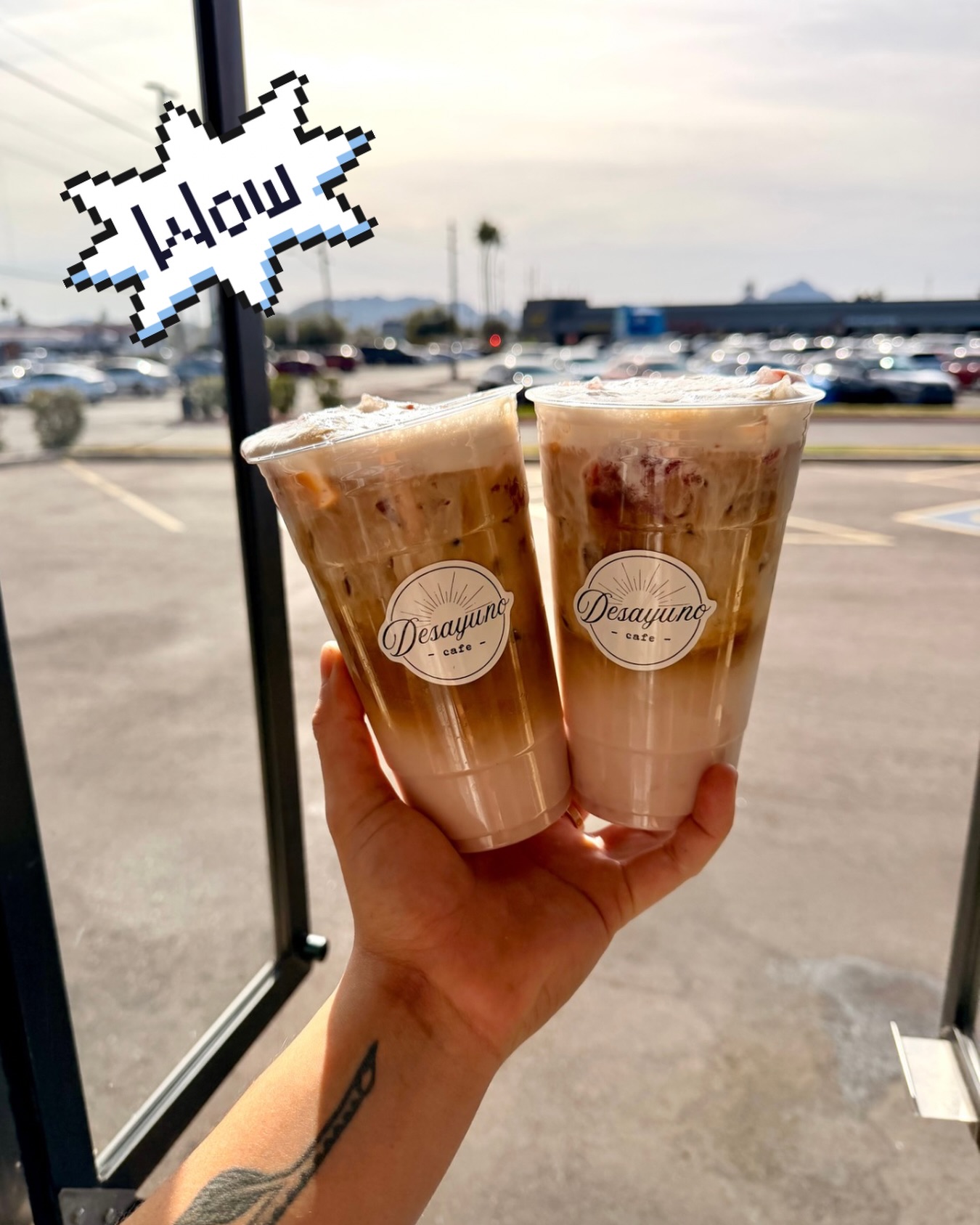 Two iced lattes held up outside